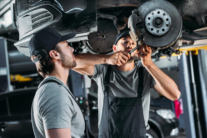Mecánicos reparando los frenos de un auto sin rueda